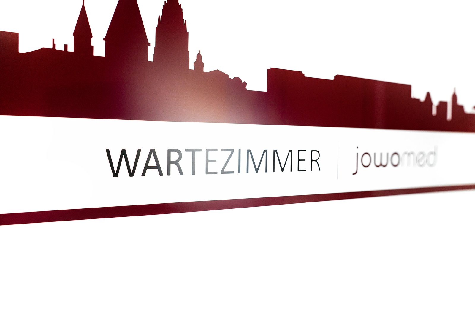 Praxisschild „Wartezimmer" mit Blick auf die Mainzer Skyline in der Praxis Jochen Wolf & Kollegen